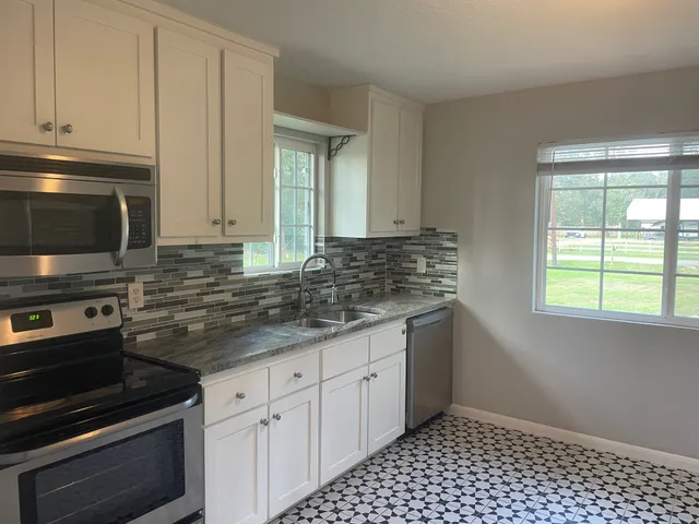 a kitchen with granite countertop a sink stove and cabinets