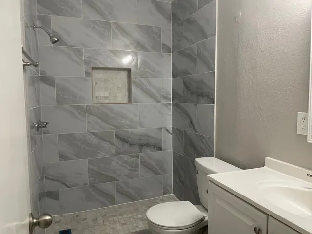 a bathroom with a sink a toilet and shower