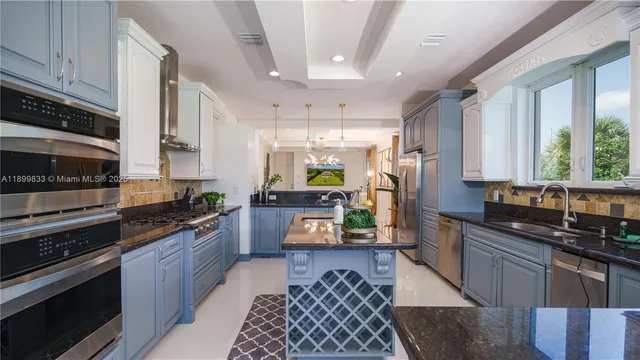 a kitchen with stainless steel appliances kitchen island granite countertop a stove refrigerator and cabinets