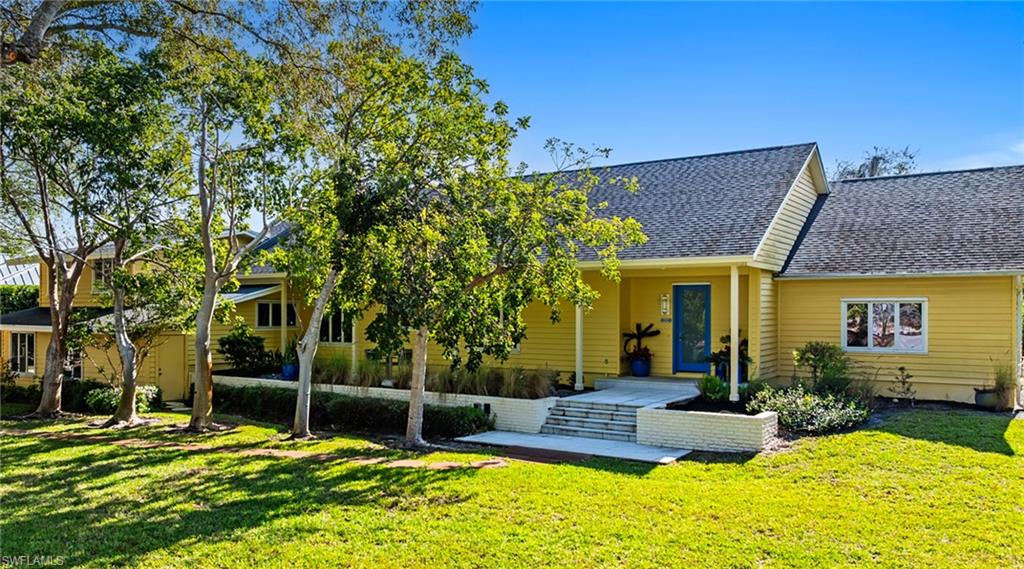 586 Yucca Road Naples, FL 34102 - Photo 2 of 26 Rear view of house featuring roof with shingles and a yard