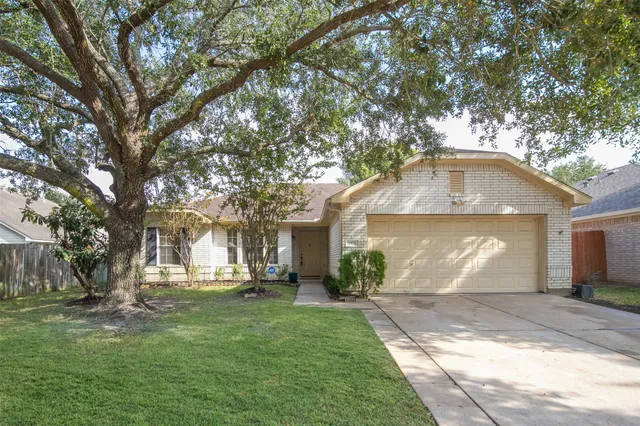 a front view of a house with a garden and trees