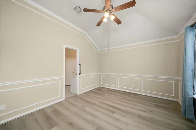 a view of an empty room with wooden floor and a ceiling fan