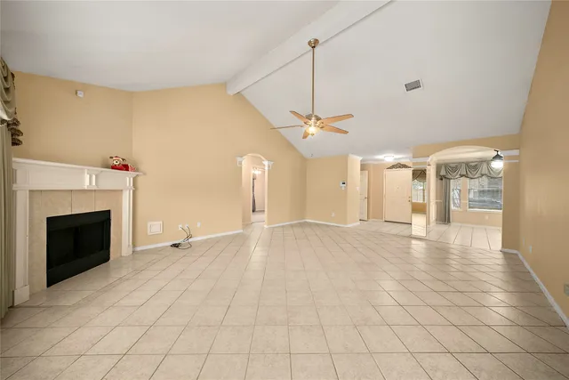 a view of an empty room with chandelier fan and fire place