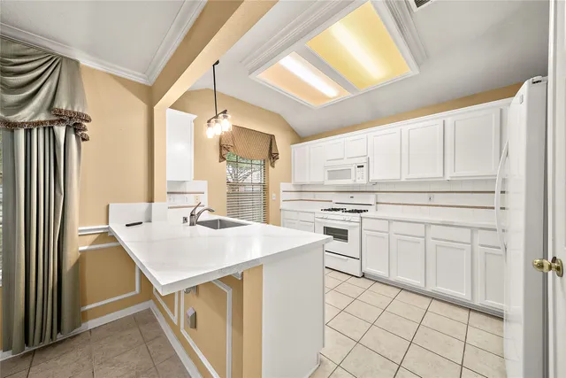 a kitchen with white cabinets appliances and a window