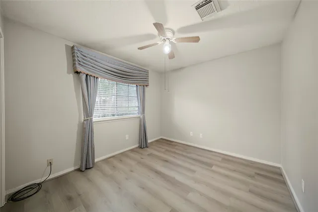 an empty room with windows and fan