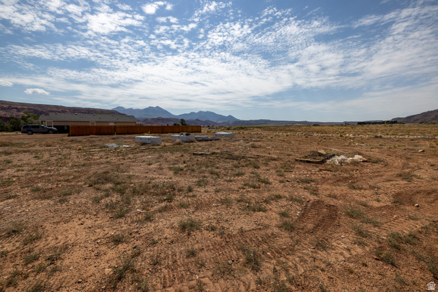 212 Lidia Circle, Unit 17 Moab, UT 84532 - Photo 20 of 24 Expansive open land with distant mountain ranges and a partially constructed building featuring a wood fence