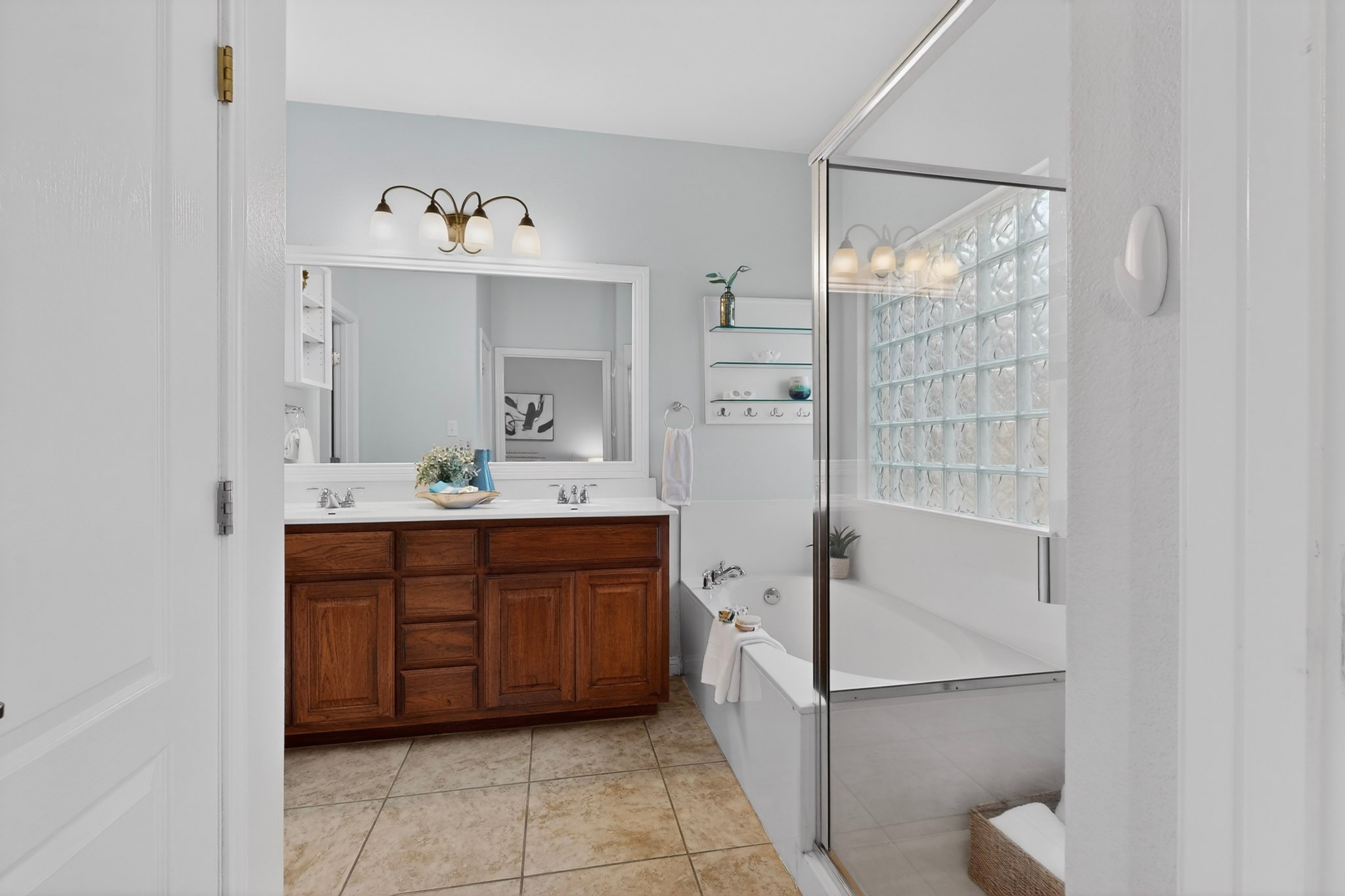 178 Limestone Trail Austin, TX 78737 - Photo 22 of 40 Bathroom featuring a dual vanity with wood-finish cabinetry and a framed mirror, a soaking tub, and a shower enclosure with glass block detailing