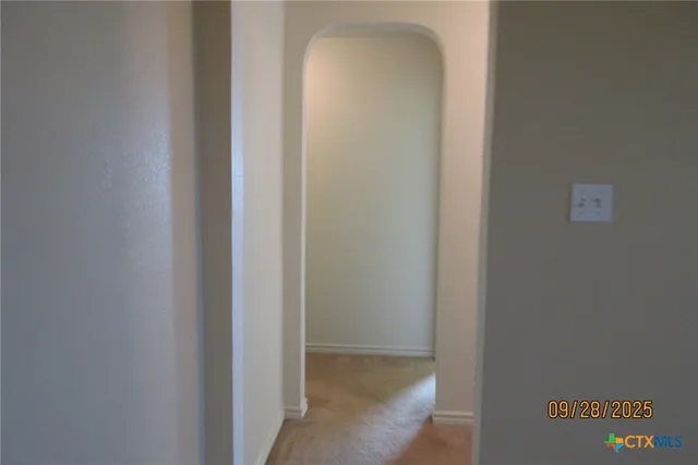 a view of an empty room with window and chandelier fan