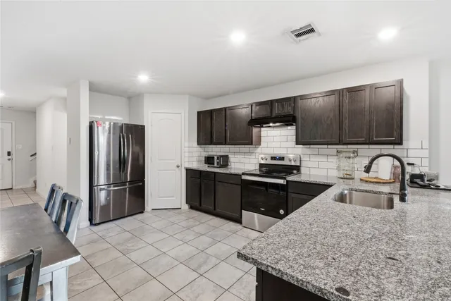 a kitchen with granite countertop a refrigerator and a sink
