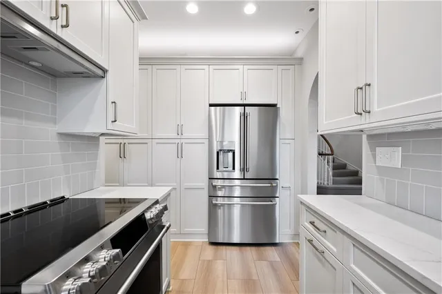 a kitchen with granite countertop a refrigerator and a stove top oven