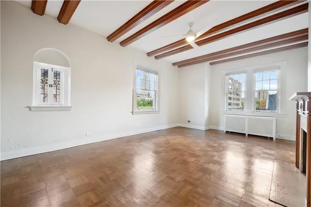 a view of an empty room with chandelier fan and wooden floor