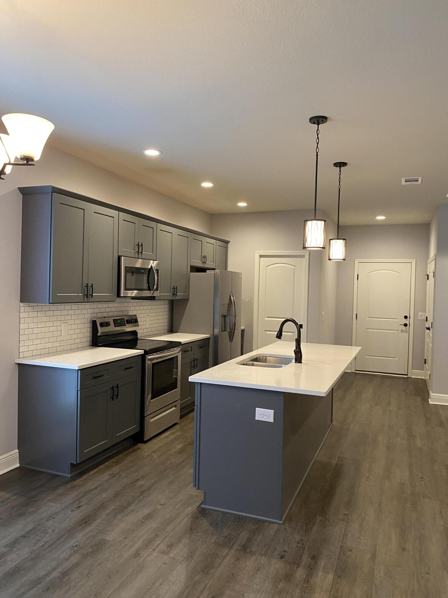 3909 Fielding Court Pace, FL 32571 - Photo 5 of 25 a large kitchen with kitchen island a stove a sink a refrigerator and a fireplace