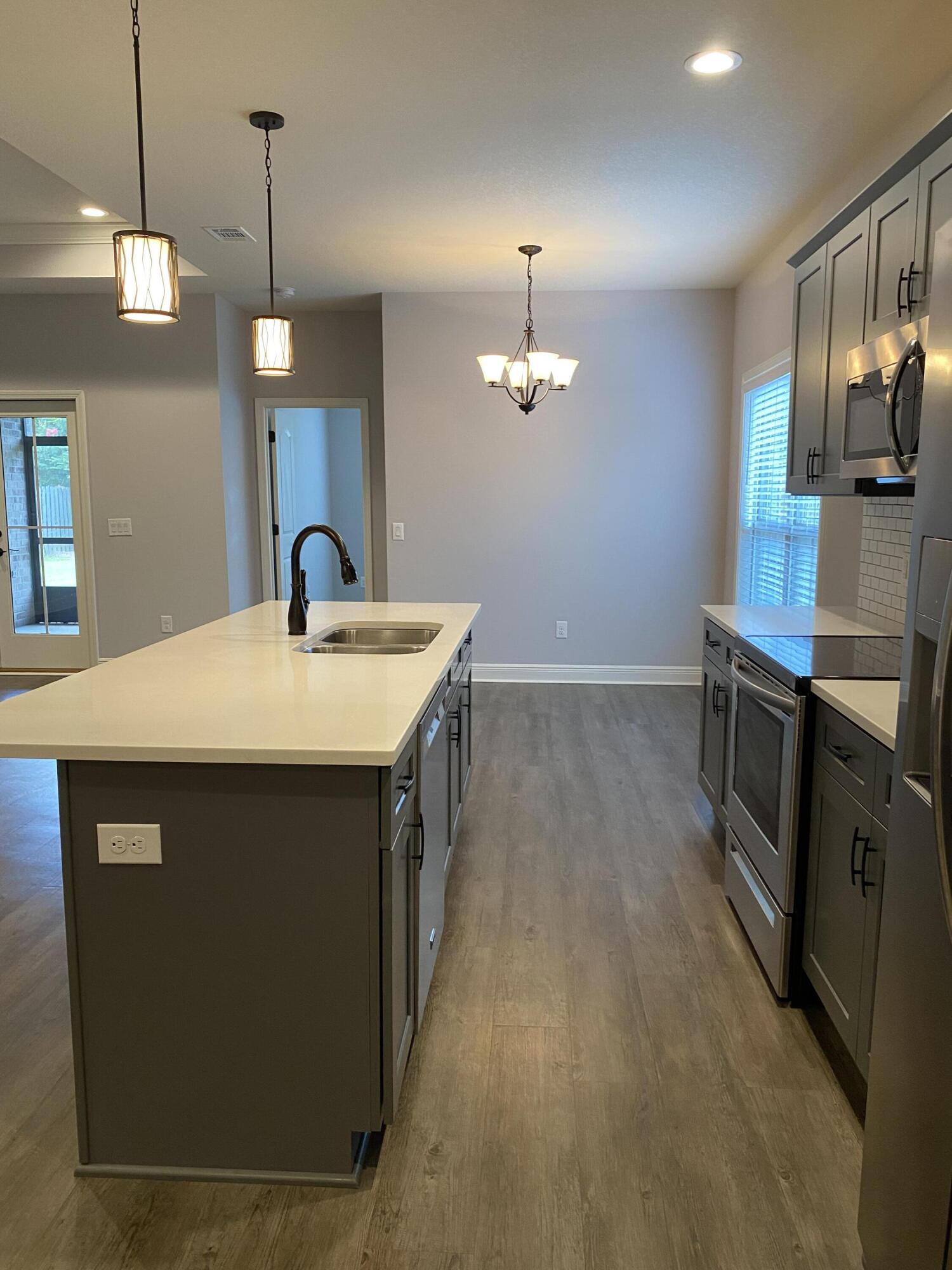 3909 Fielding Court Pace, FL 32571 - Photo 6 of 25 a kitchen with stainless steel appliances a sink stove and wooden floor