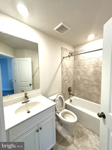a bathroom with a granite countertop sink toilet a mirror and shower