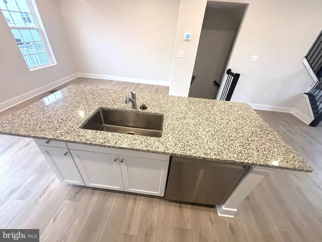 a kitchen with granite countertop a sink and a wooden floor