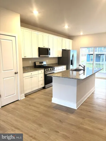 a kitchen with stainless steel appliances granite countertop a stove top oven a sink dishwasher and a refrigerator with wooden floor