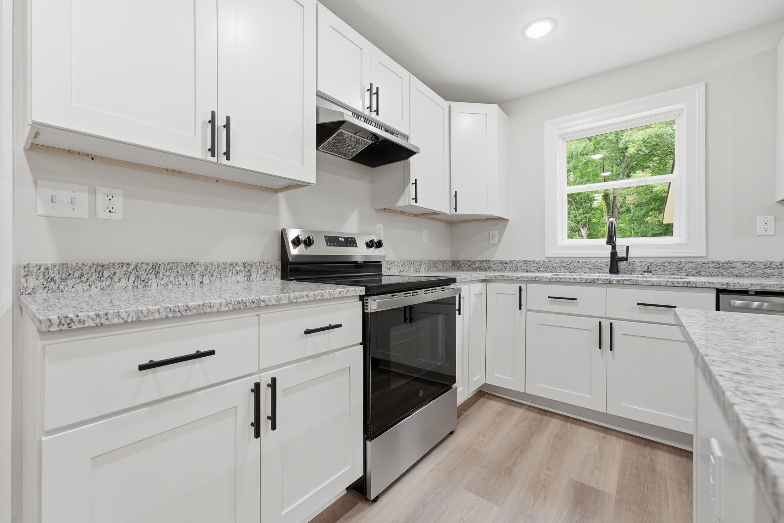 4683 Belmont Road Hernando, MS 38632 - Photo 12 of 21 Contemporary kitchen featuring white shaker cabinetry with matte black hardware, granite countertops, and wood-finish flooring