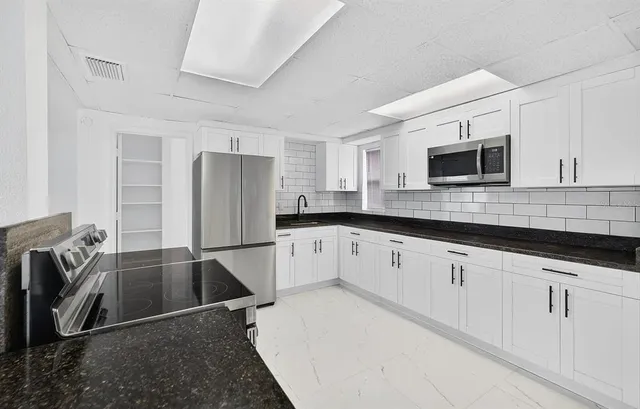 a kitchen with granite countertop a refrigerator stove and microwave