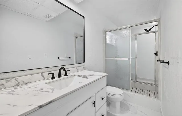 a bathroom with a granite countertop sink toilet and shower