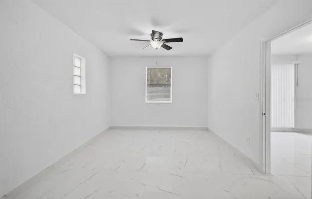 an empty room with a window and a ceiling fan