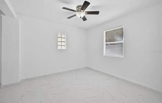 an empty room with a window and a fan