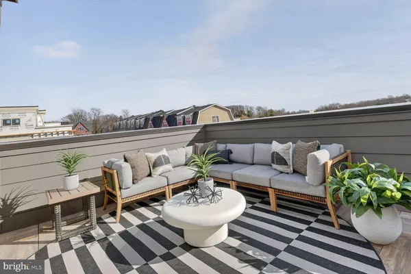 a roof deck with table and chairs and potted plants