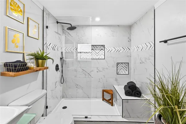 a bathroom with a tub a potted plant and a shower