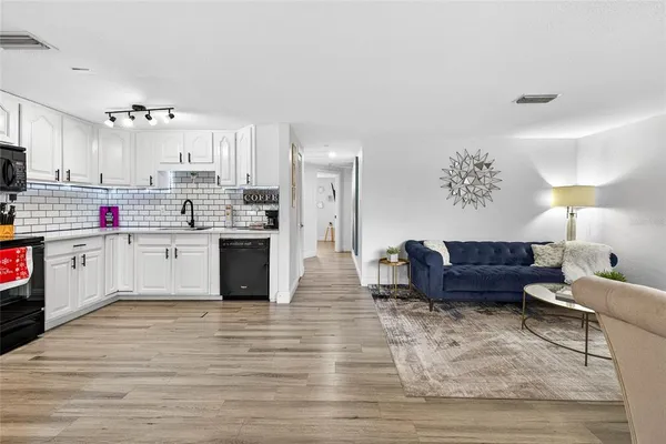 a kitchen with stainless steel appliances kitchen island granite countertop a stove a sink and white cabinets