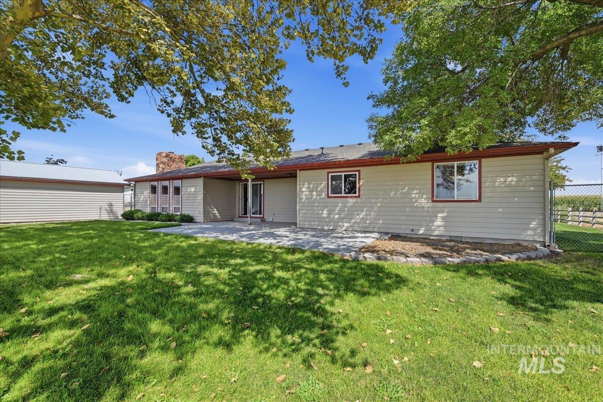 26201 Hop Road Caldwell, ID 83607 - Photo 31 of 45 Expansive lawn area with a stone patio, mature trees, and a detached outbuilding