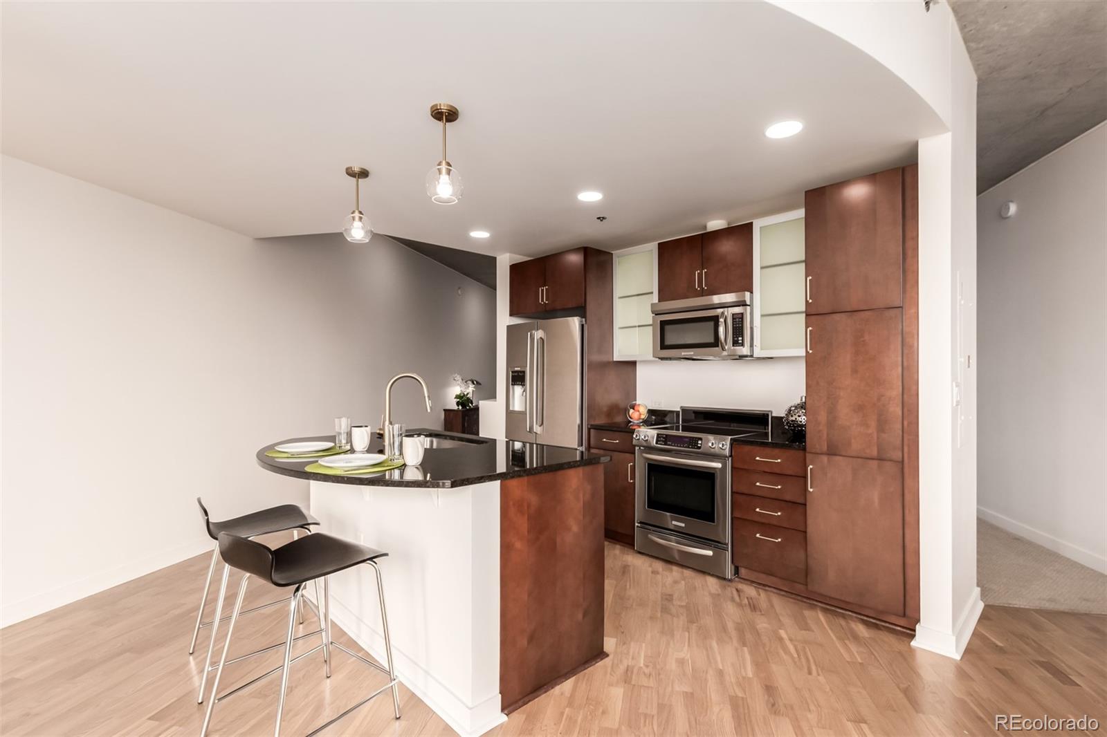891 14th Street, Unit 3812 Denver, CO 80202 - Photo 14 of 50 a kitchen with kitchen island stainless steel appliances a sink a stove a refrigerator cabinets and a dining table