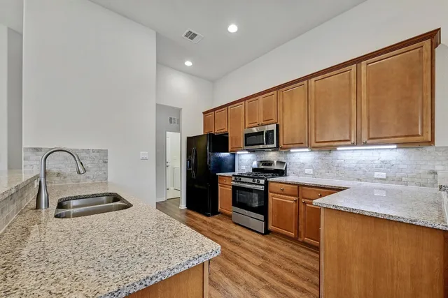 a kitchen with stainless steel appliances granite countertop a stove top oven a sink dishwasher a refrigerator and cabinets with wooden floor