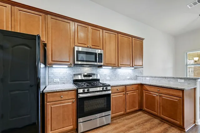 a kitchen with granite countertop wooden cabinets stainless steel appliances and a window