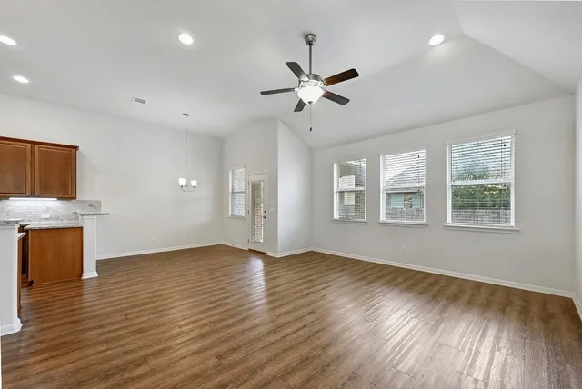 a view of an empty room with a window and wooden floor