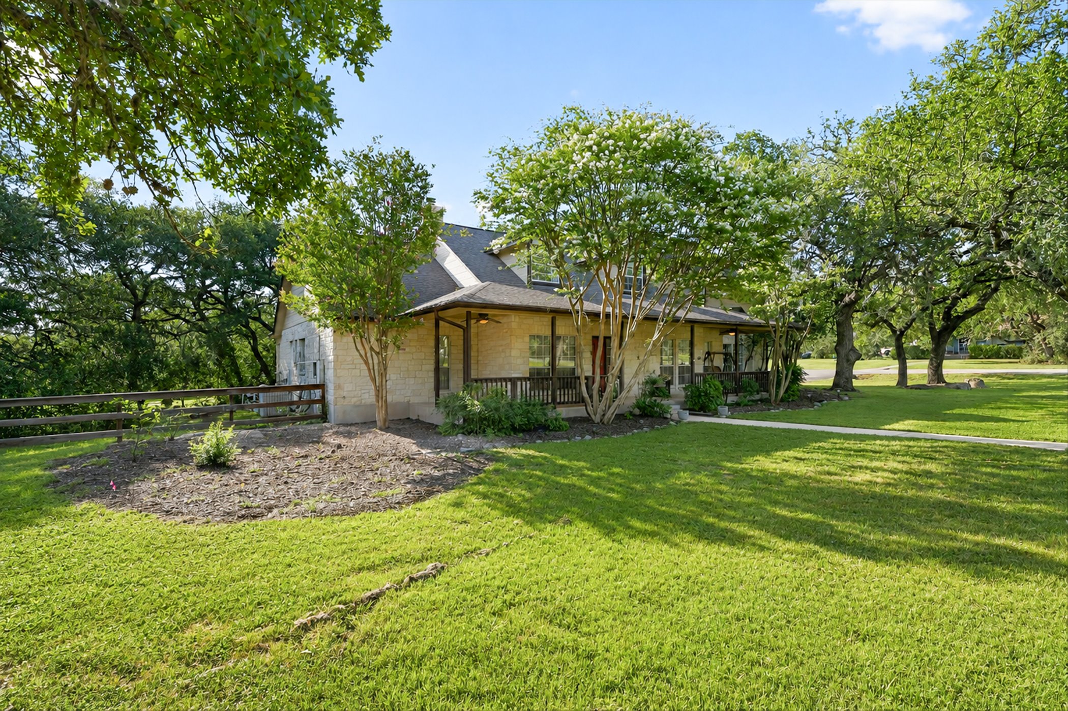 13615 Copperleaf Trail Manchaca, TX 78652 - Photo 3 of 38 Mature trees frame this inviting stone residence, offering a serene outdoor setting.