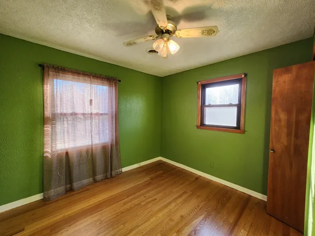 a view of an empty room with window and wooden floor
