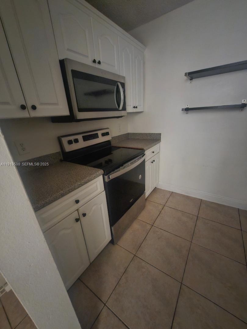 8240 Southwest 210th Street, Unit 220 Cutler Bay, FL 33189 - Photo 14 of 23 a kitchen with a stove and a microwave