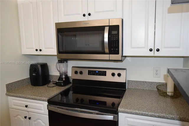 a kitchen with white cabinets and appliances