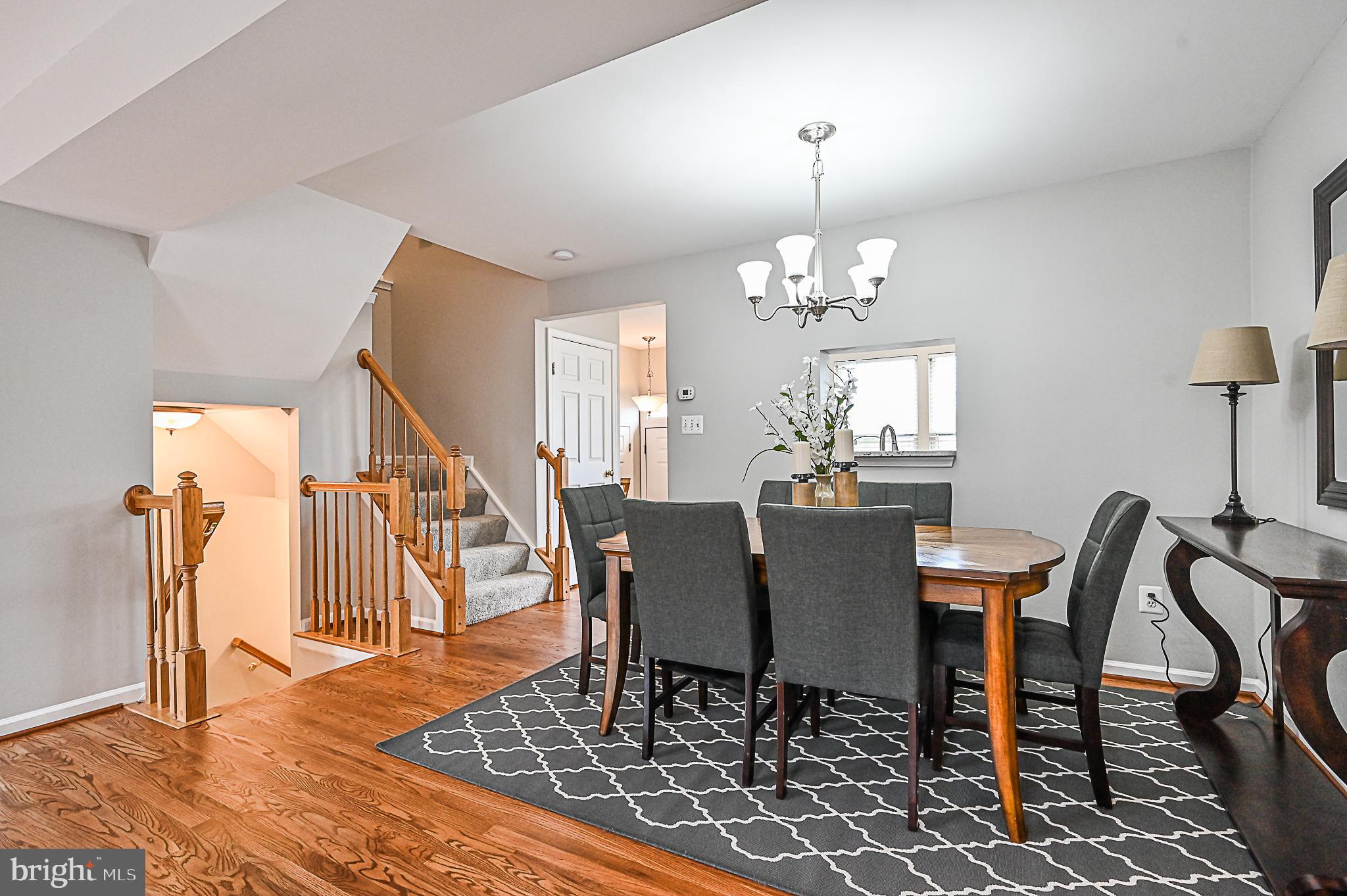 6356 Racetec Place Springfield, VA 22150 - Photo 18 of 51 a dining room with wooden floor a chandelier a wooden table and chairs