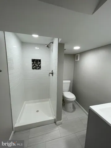 a bathroom with a granite countertop toilet a sink and a mirror