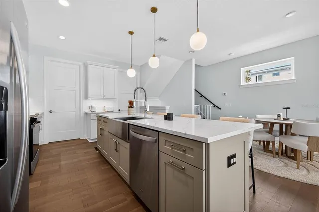 a kitchen with a sink a counter top space stainless steel appliances and a center island