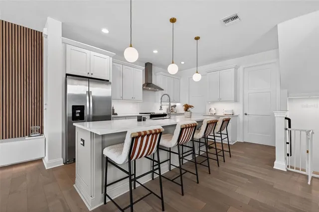 a kitchen with stainless steel appliances a dining table chairs and white cabinets