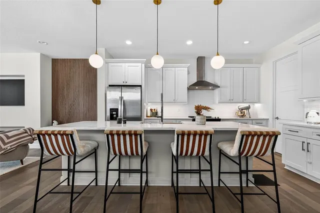 a kitchen with stainless steel appliances a dining table chairs and white cabinets