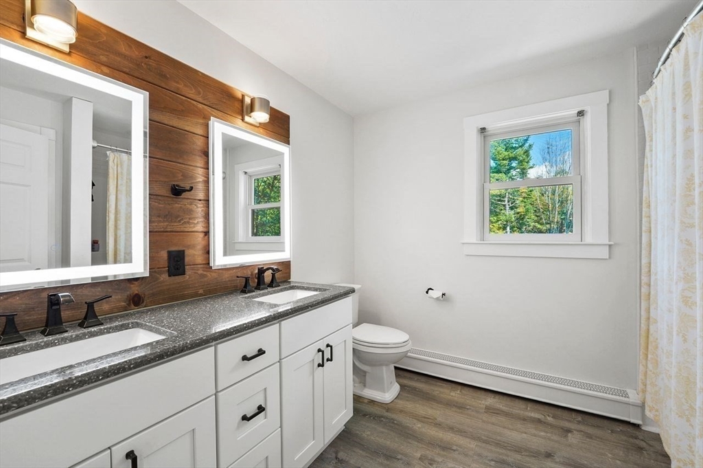31 Douglas Road Sutton, MA 01590 - Photo 27 of 42 a bathroom with a granite countertop sink a toilet a mirror and window