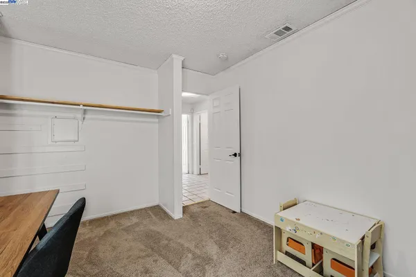 a bed sitting in a bedroom next to a window and a chair