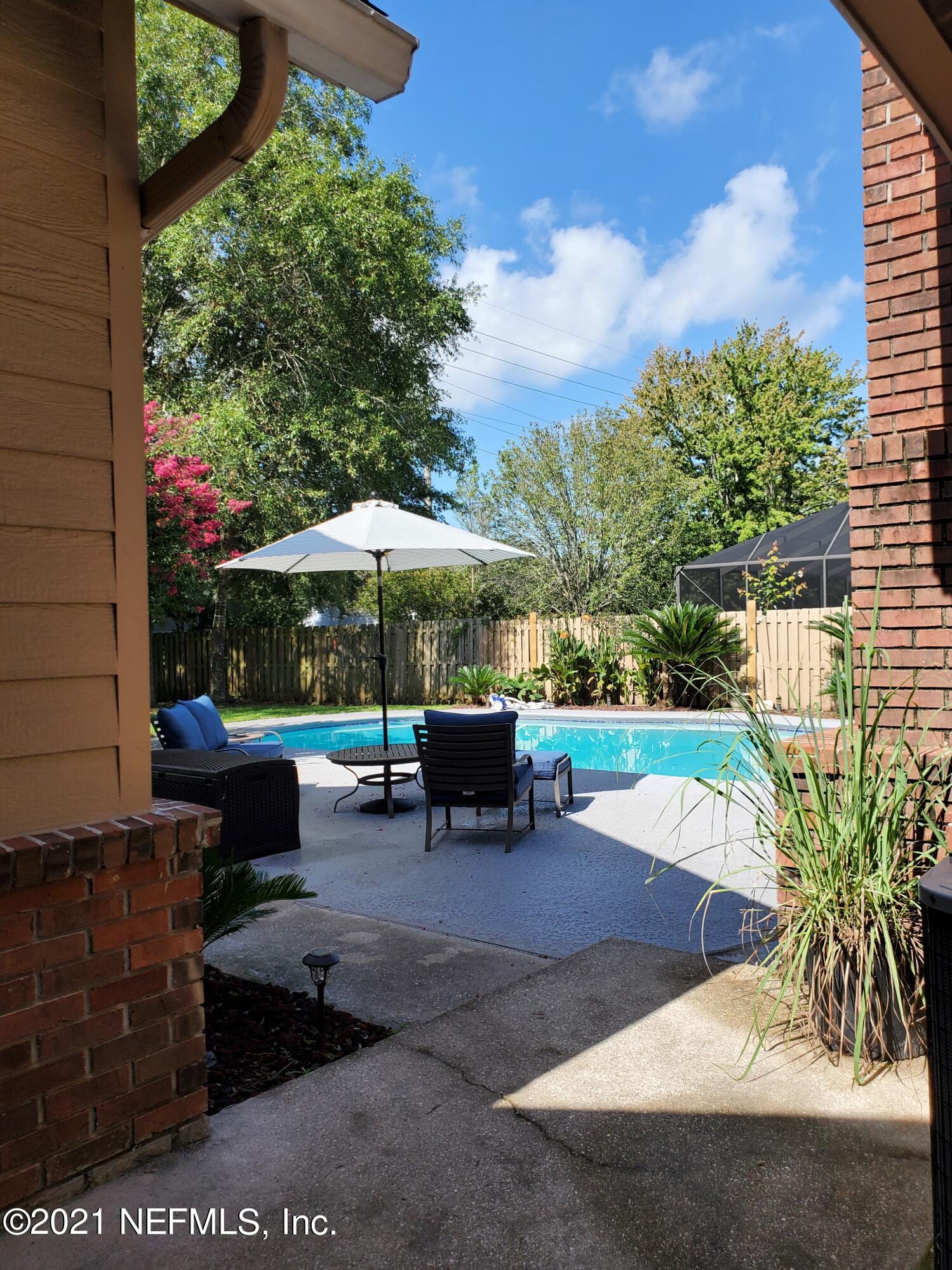 3047 Nautilus Road Middleburg, FL 32068 - Photo 34 of 37 a view of a patio with table and chairs under an umbrella with a fire pit