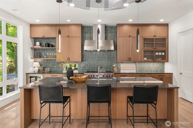 a kitchen with stainless steel appliances granite countertop a stove top oven a sink a dining table and chairs