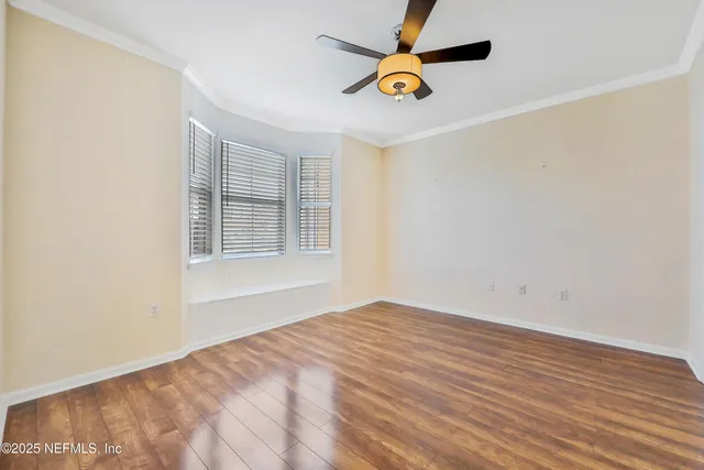 an empty room with a window and ceiling fan