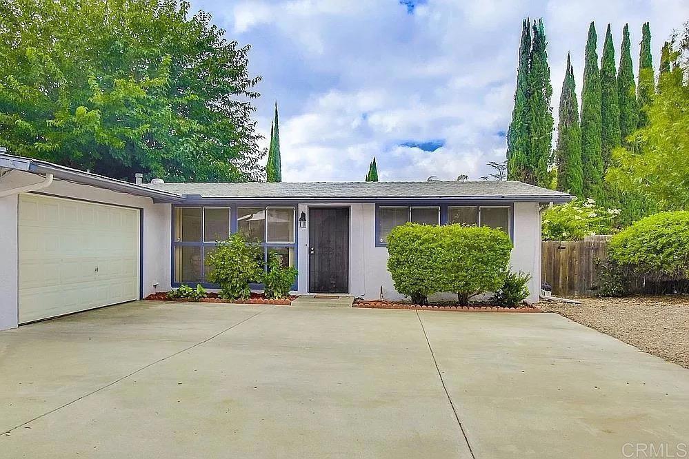 a view of a house with potted plants and a large tree