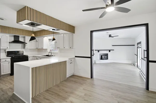 a kitchen with kitchen island a counter top space wooden floor stainless steel appliances and cabinets