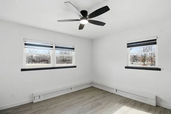 an empty room with wooden floor and ceiling fan